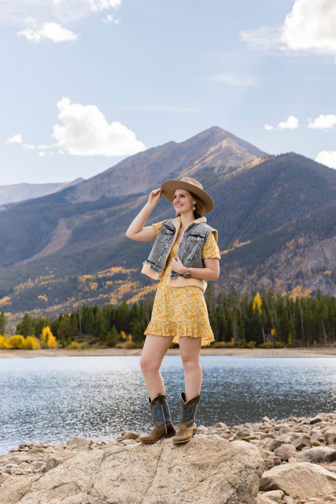 Senior wearing a wide brimmed hat, vest and boots for fall photo session in Colorado