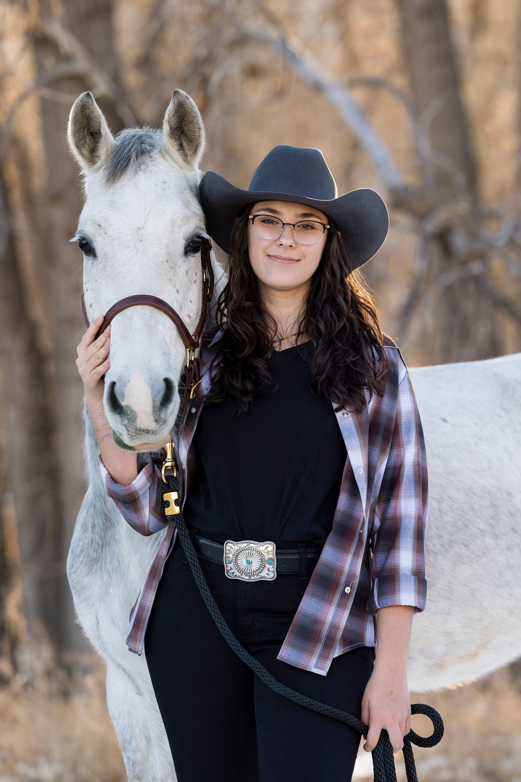high school senior girl with her horse wearing a flannel and cowboy hat in Colorado