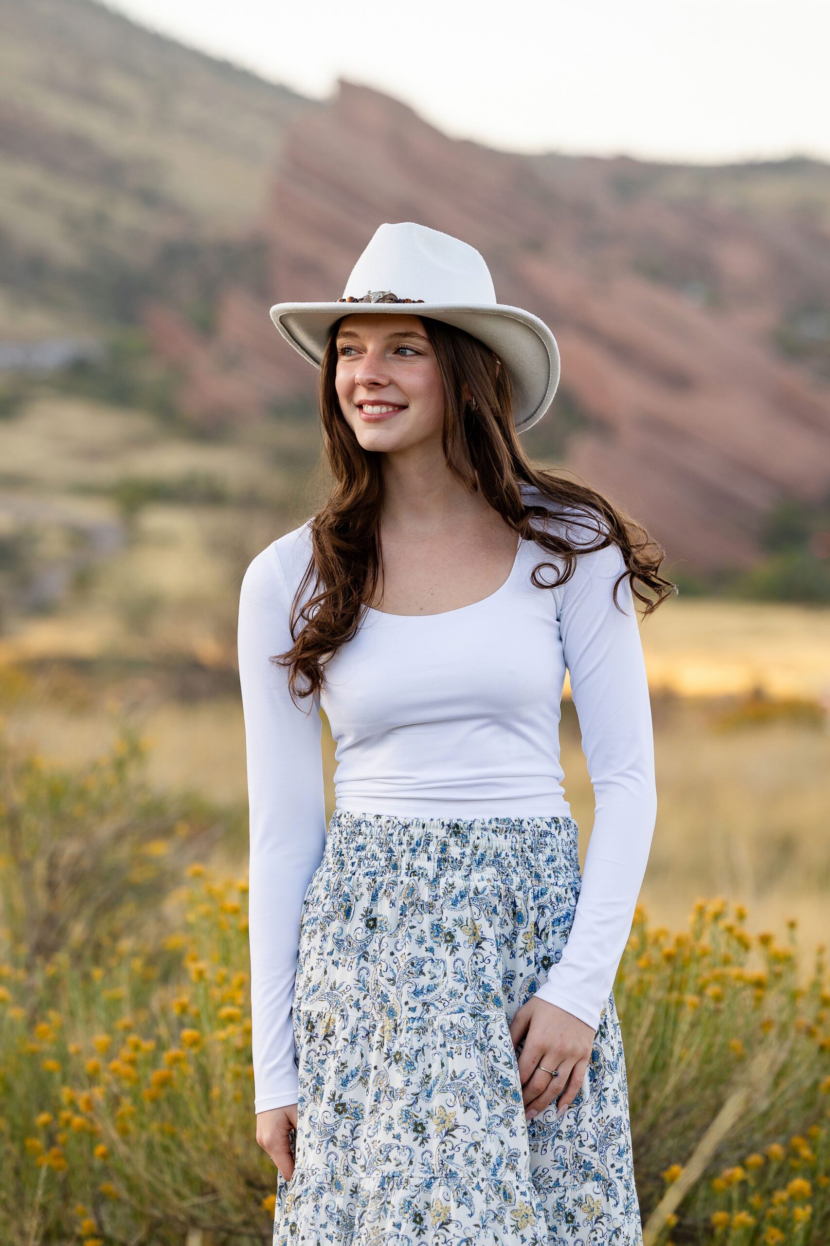 Senior wearing a wide brimmed hat for fall portraits outside Red Rocks